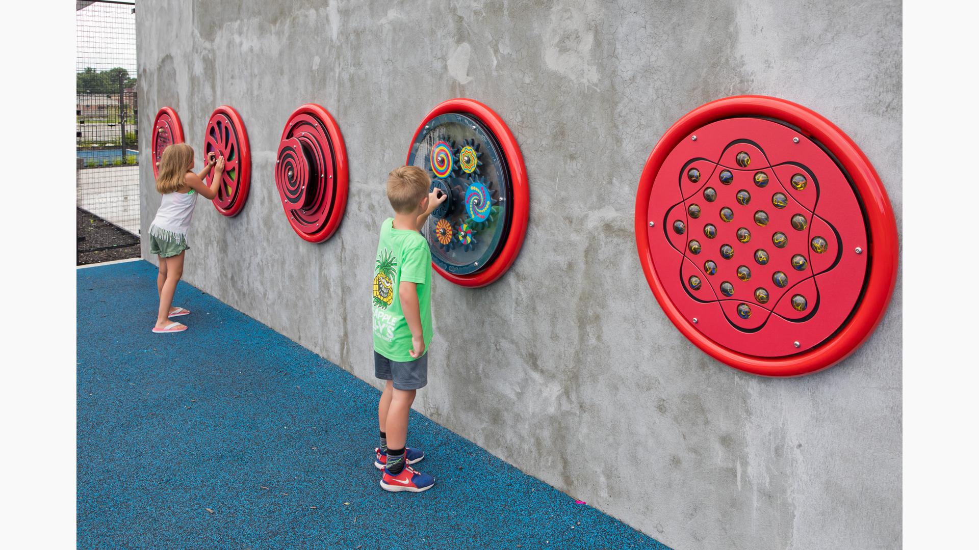 A boy and girl playing with wall mounted games at Prairie Creek Park.
