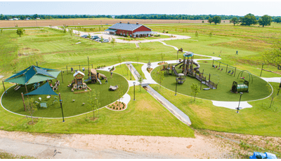 Large nature-inspired playground with two play areas for kids of all ages. Some parts are covered by large shade structures