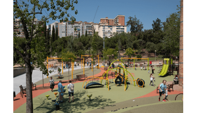 Full view of a large open play area with inclusive safety surfacing with multiple play structures for all ages along with a zip line and swing set area.