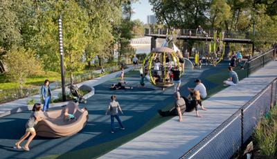 Families gather for relaxation and play at Promenade Park. A group of kids pile into the We-Go-Round. The Global Motion is filled with kids-both inside and out. Adults sit on the sidewalk looking on.