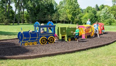 Kids play on the different colored train cars of a play structure. 