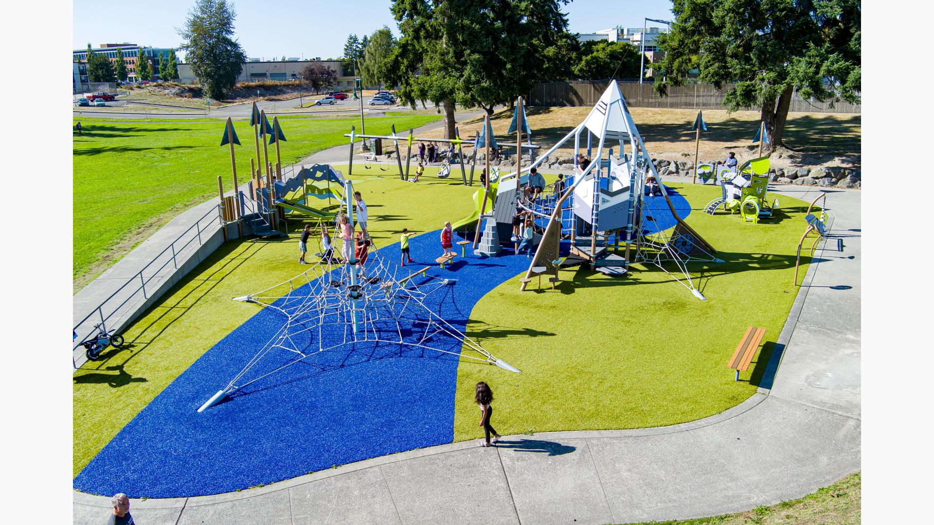 Elevated view of a mountain and nature themed playground filled with children.