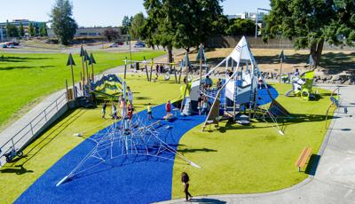 Elevated view of a mountain and nature themed playground filled with children.