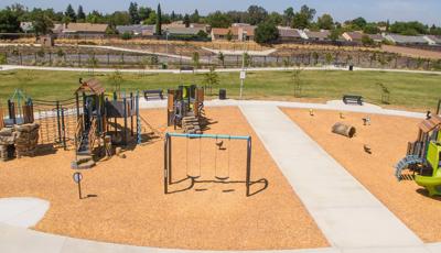 Elevated full view of a large play space with multiple play structures with rope climbers, artificial rock and log climbers, and recycle wood plank panels and roofs.