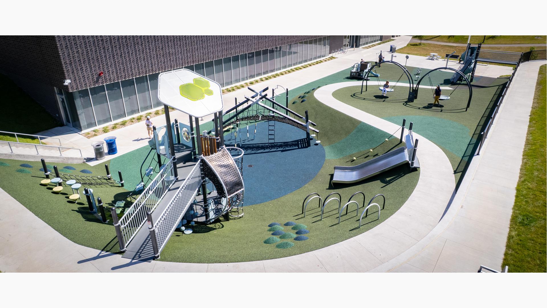 Elevated view of a playground set next to a community center building. 