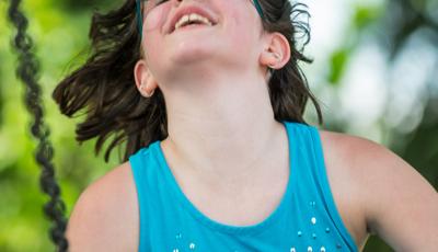 Girl in sunglasses enjoys riding a swing