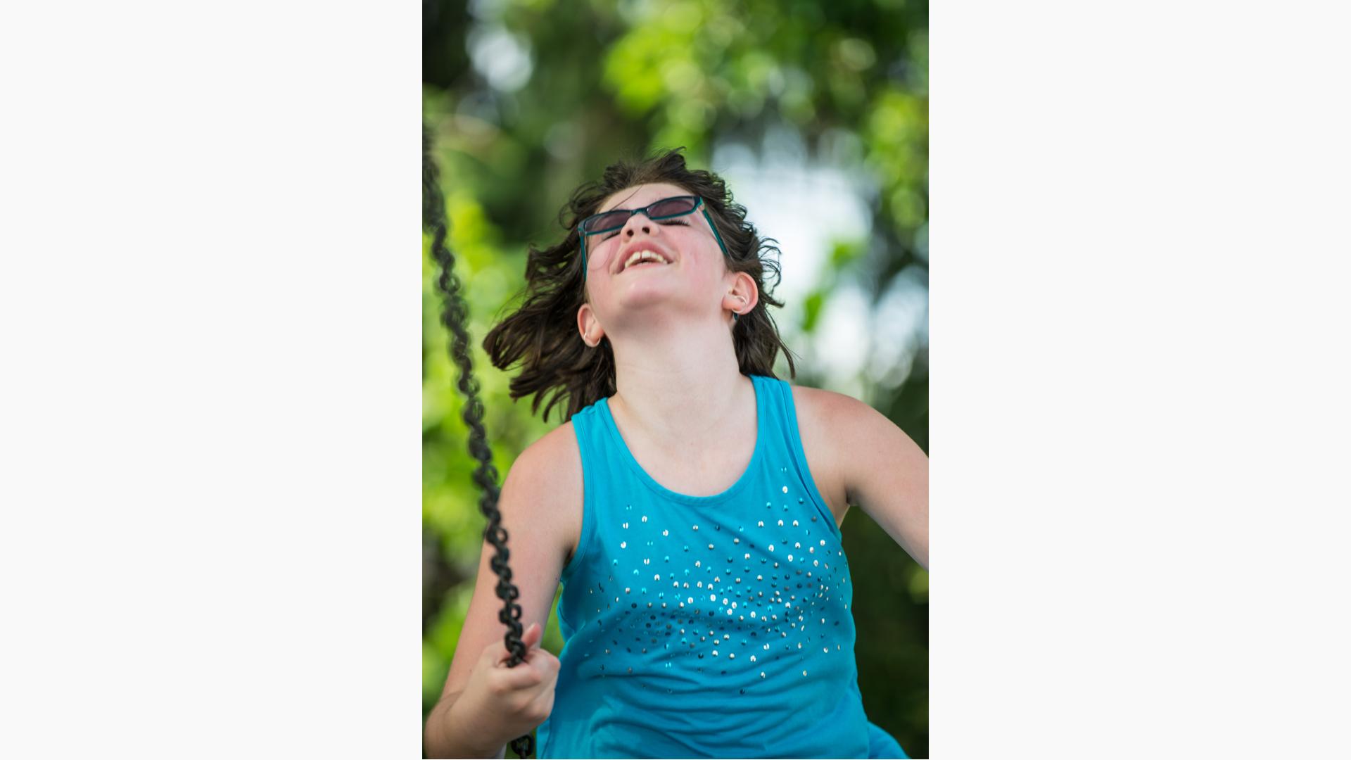 Girl in sunglasses enjoys riding a swing