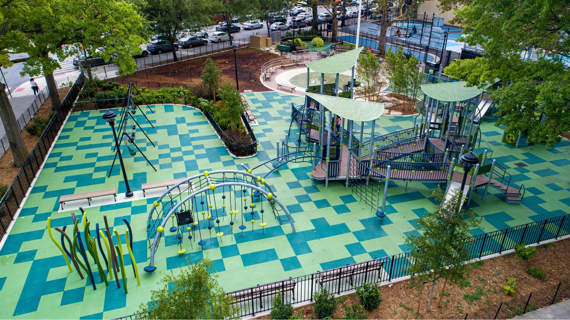 Elevated view of a city nature themed playground with scattered square safety tile surfacing in different shades of green.