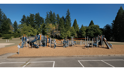 Many children playing on PlayBooster play structure. A boy and girl swing on Overhead events. Other kids play on slides climber and across bridges.