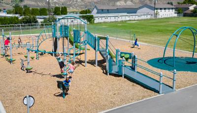 Children play on a elementary school playground next to a large open grass field.