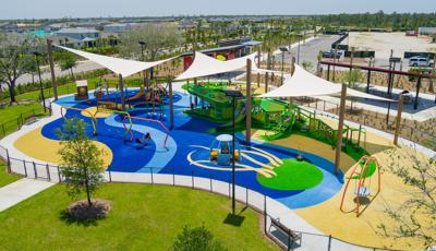 Elevated view of large shade sails cover a large water themed play area with unique crocodile play structure. 