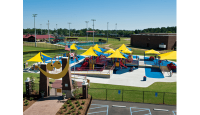 All inclusive playground covered in CoolToppers shade system with Baseball fields in background. Smiling gateway in foreground.
