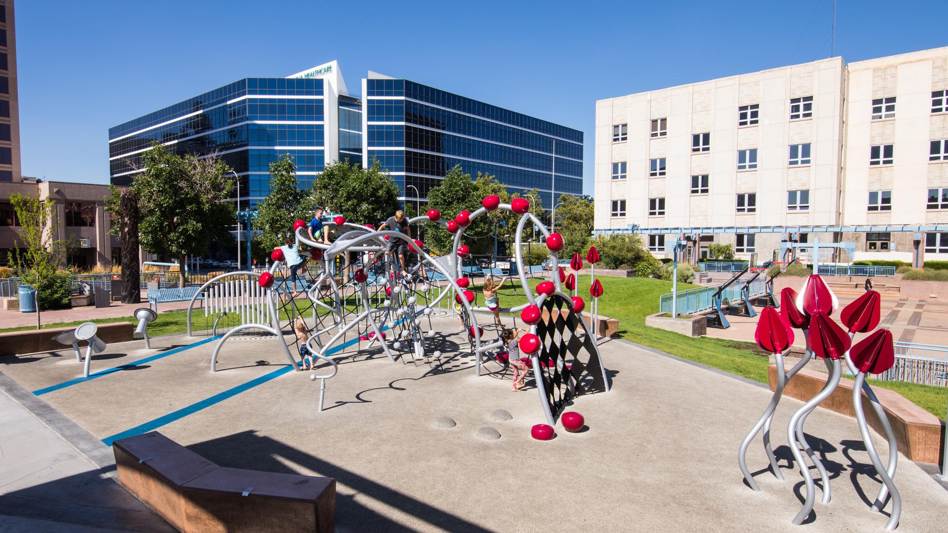 Children playing on an artistic, sculptural playground made to look like a Prickly Pear Cactus with bright red fruit