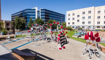 Children playing on an artistic, sculptural playground made to look like a Prickly Pear Cactus with bright red fruit