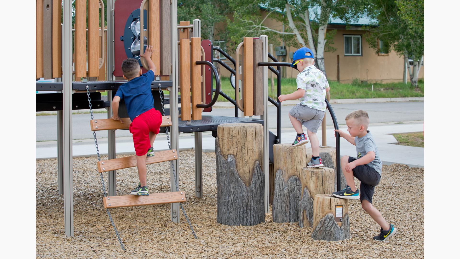 Boys climbing on Log Climbers and little boy in red shorts climbs ladder