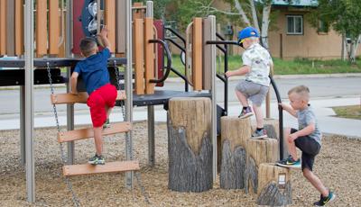 Boys climbing on Log Climbers and little boy in red shorts climbs ladder