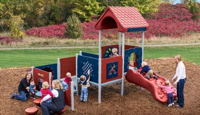 Mothers play with their children on a toddler accessible playground structure.  