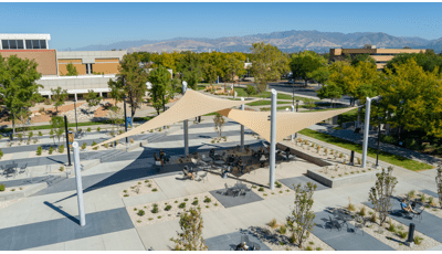 Elevated view of two large shade sails cover a seating area in an outdoor court yard.