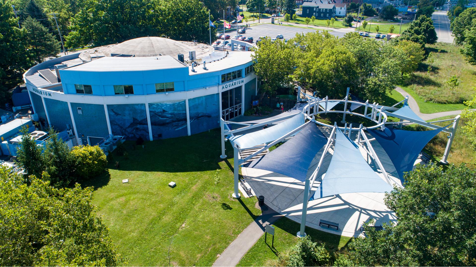 Elevated view of a circular building with a custom matching circular shade system made up of triangular shade sails colors in navy and white blue covering a courtyard sitting area.