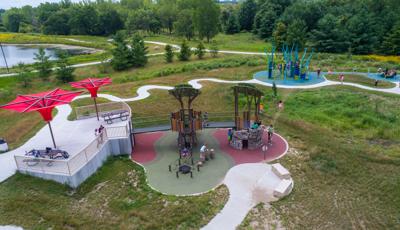 Kids running between the nature inspired play structure and the PlayBooster climber play structure.