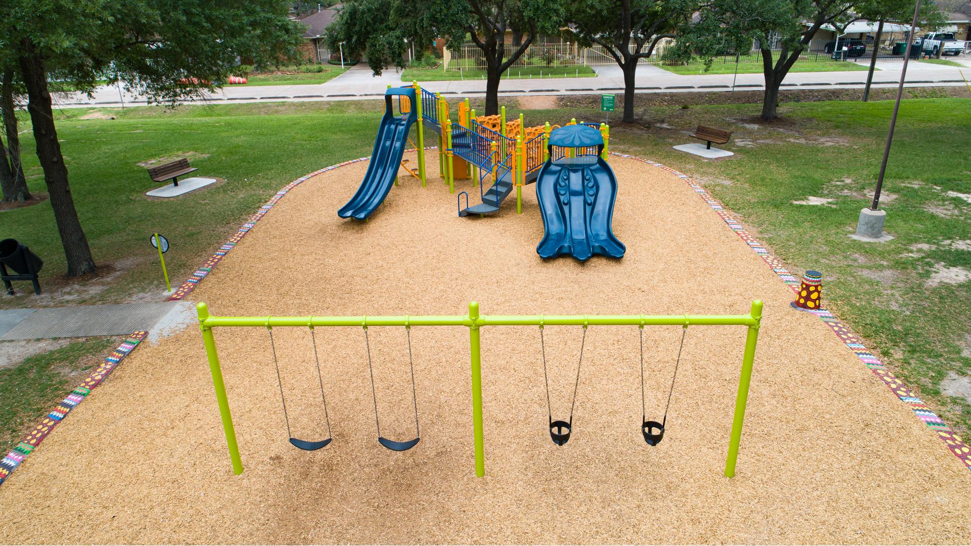 Outdoor community park play area with single play structure and a row of swings.