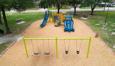 Outdoor community park play area with single play structure and a row of swings.