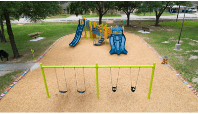 Outdoor community park play area with single play structure and a row of swings.