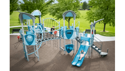 Children play on a park playground colored with different shades of blues and greys with multiple rope climbers, slides, and play panels.