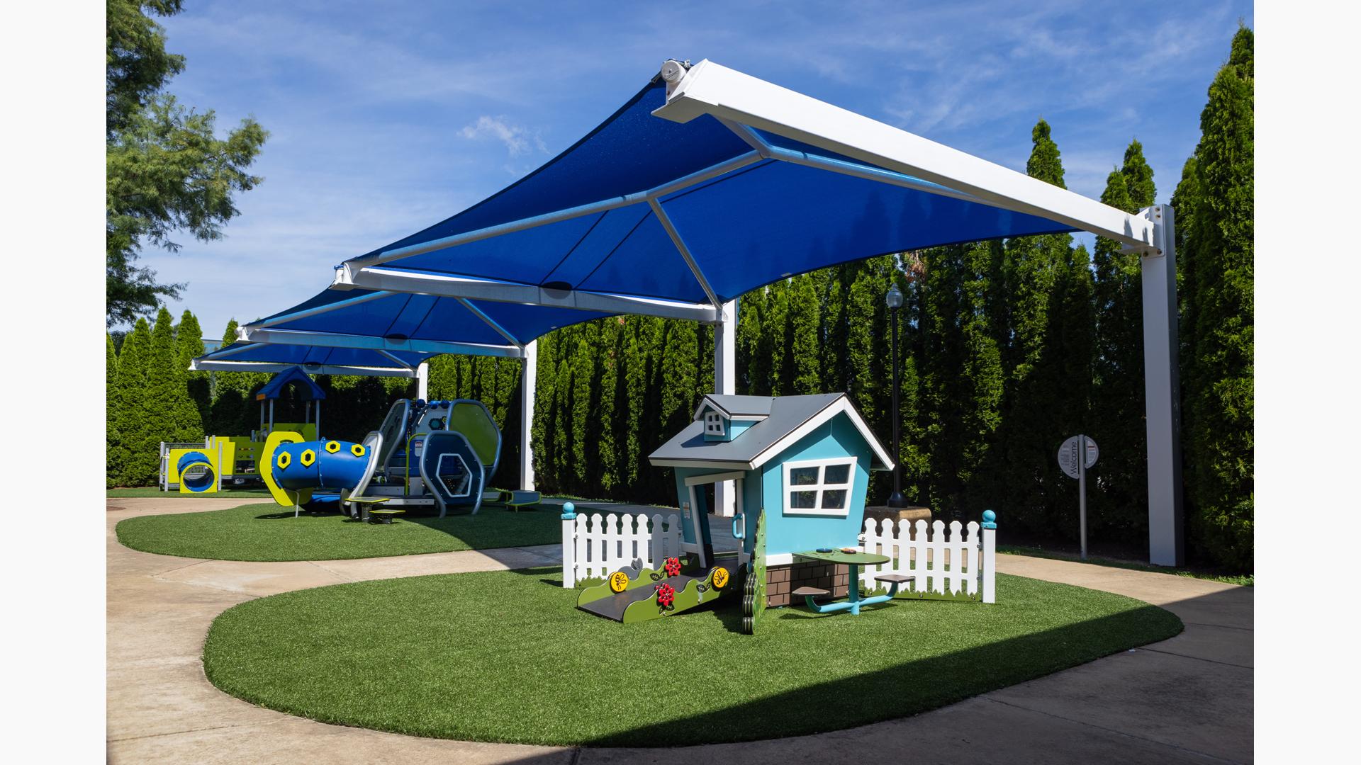 Three large blue rectangular shades cover three separate play structures for young children. 