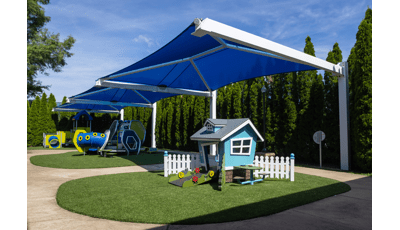 Three large blue rectangular shades cover three separate play structures for young children. 