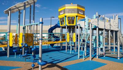 Play structure made of ramps, climbers and slides designed like an airport control tower and jet airplane.
