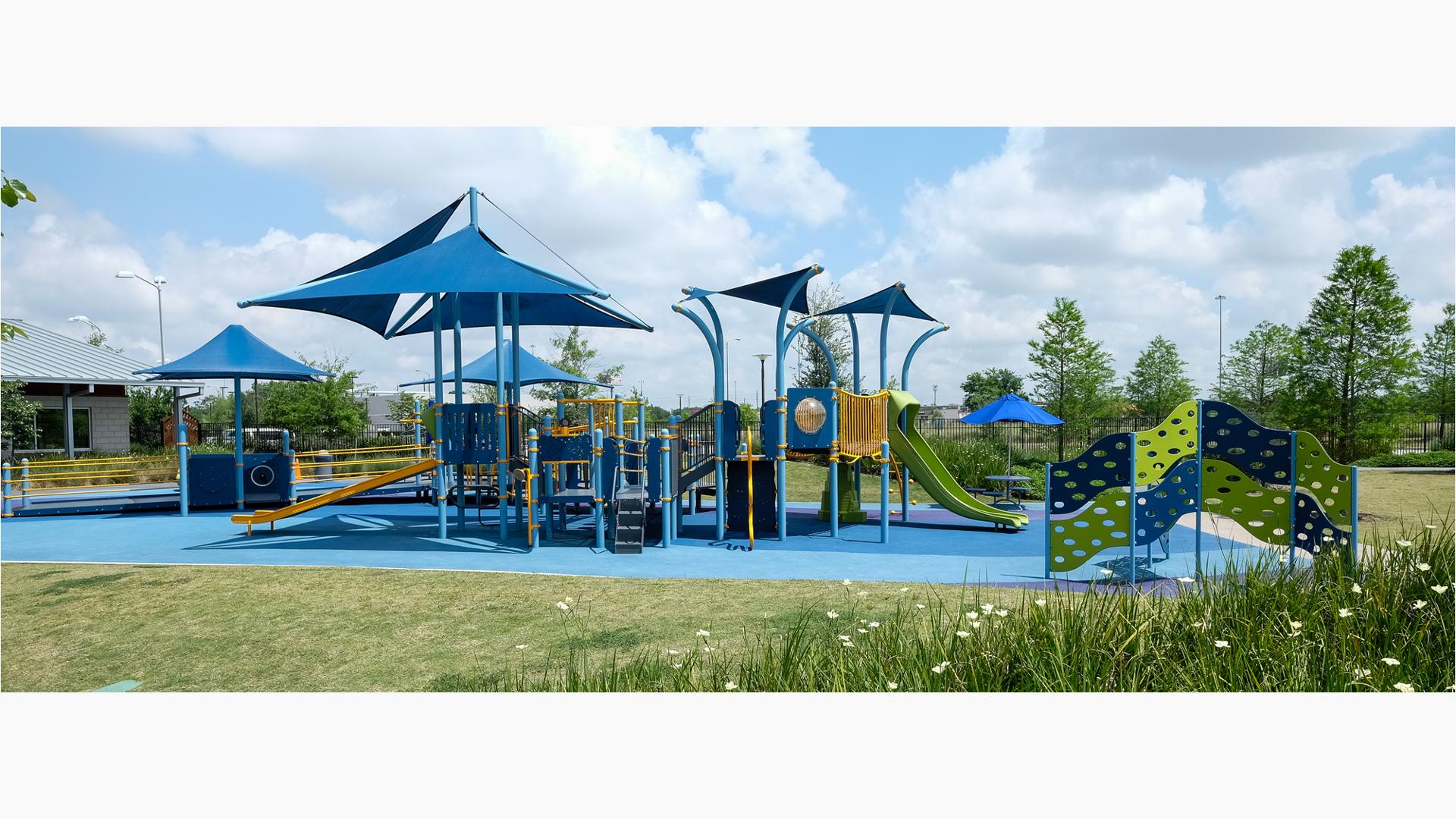 Dylan Park is home to a brightly colored PlayBooster® playstructure featuring the Sway Fun® Glider, Rollerslide and OmniSpin® Spinner. The Cascade Climber and a Sensory Play Center® and several CoolToppers® shade products.