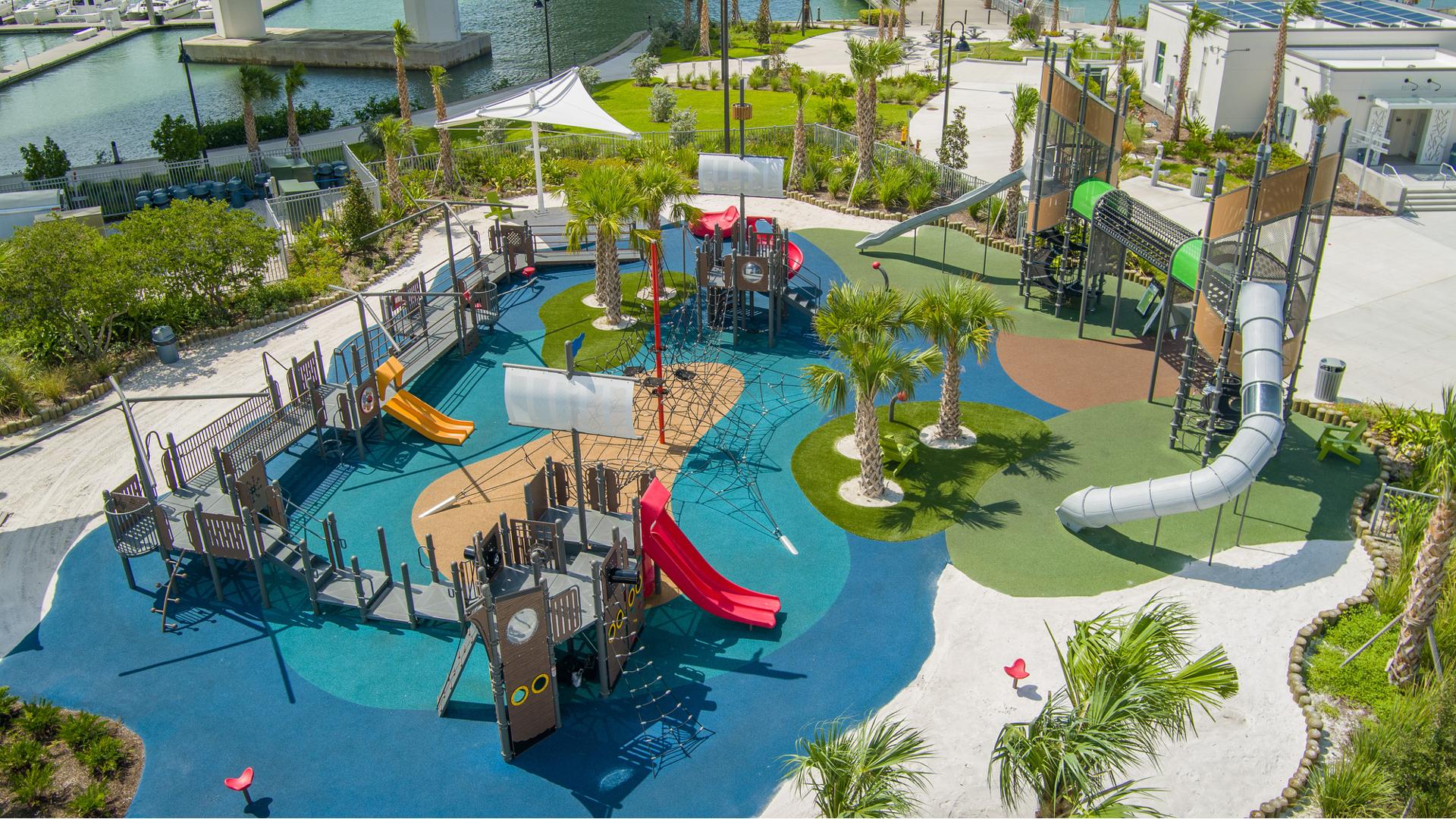 Elevated view of a boat/ocean themed playground with two separate play structures one designed as a boat while the other is a unique two tower structure connected by a elevated crawl tunnel.