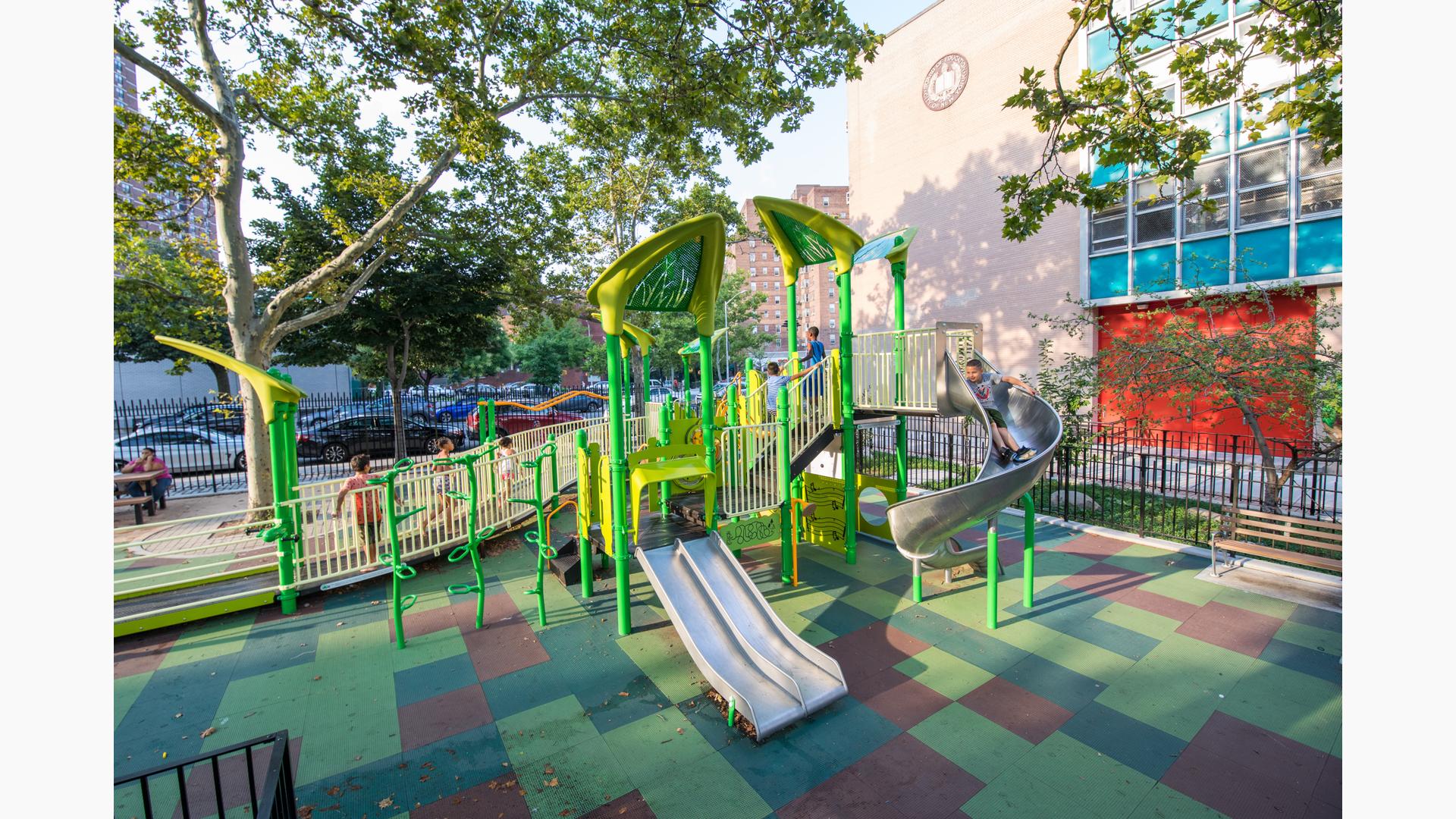 Children run on ramp as boy rides down slide.