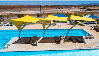 Three bright yellow shade structures covering lounge chairs in pool area. 