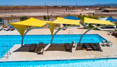 Three bright yellow shade structures covering lounge chairs in pool area. 