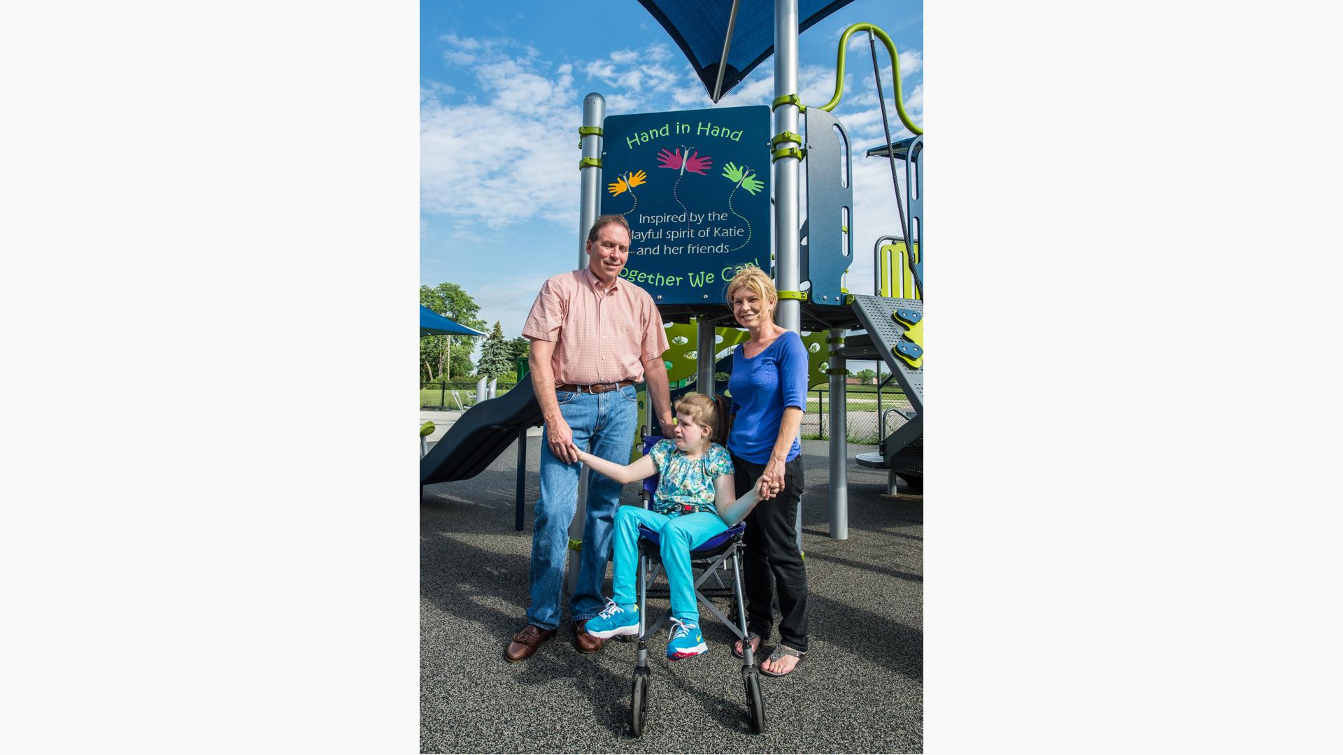 Girl stands with family holding hands in front of "hand in hand" sign