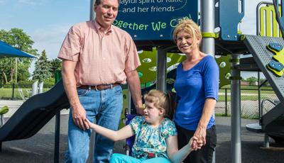 Girl stands with family holding hands in front of "hand in hand" sign