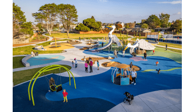 Elevated view of families playing at a park playground with the main play structure designed like large white birds.