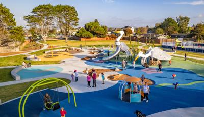 Elevated view of families playing at a park playground with the main play structure designed like large white birds.