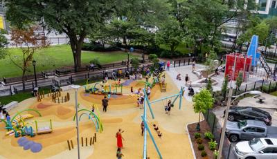 Elevated view of a colorfully surfaced city park  with building inspired play structure and modern themed freestanding play activities. 