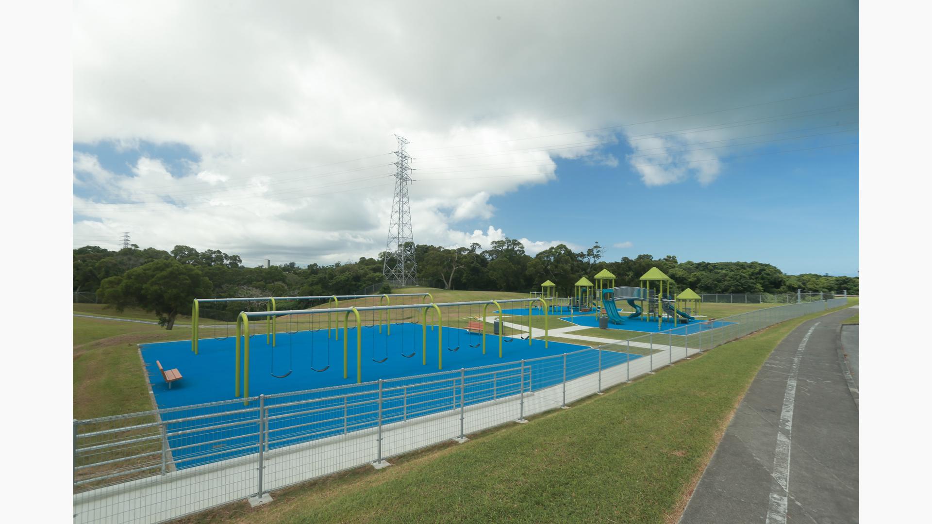 A large open play space has multiple bays of swings and a large play structure to the right.