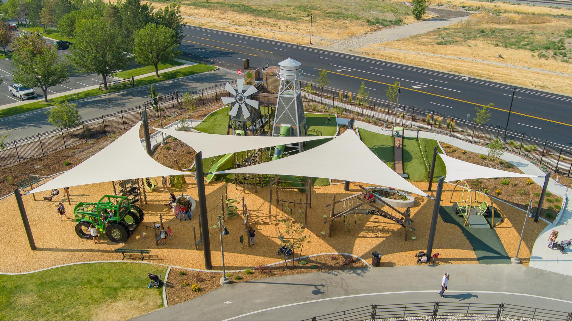 Elevated view of large tan triangular shades covering a playground play area.