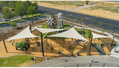 Elevated view of large tan triangular shades covering a playground play area.