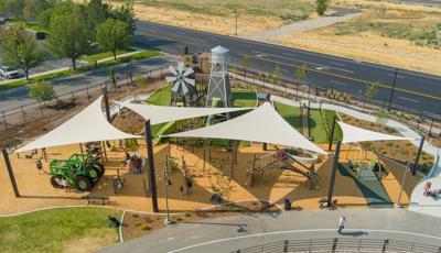 Elevated view of large tan triangular shades covering a playground play area.