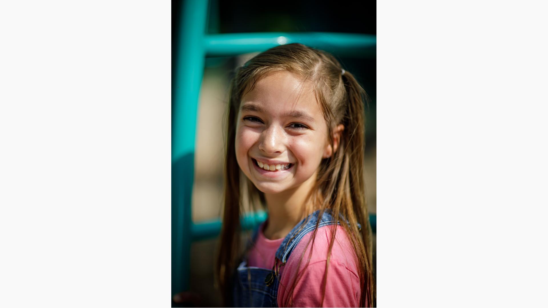 Girl in pink shirt and overalls smiling