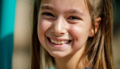 Girl in pink shirt and overalls smiling