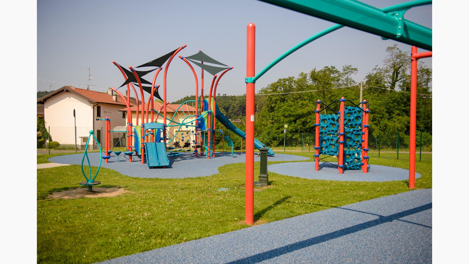 A brightly colored neighborhood playground colored in oranges and teals with climbers, slides, zipline ride, and spinners.