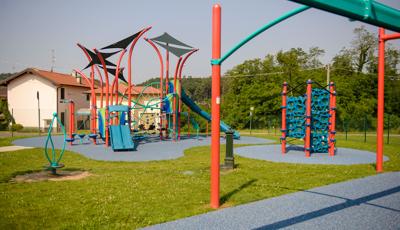 A brightly colored neighborhood playground colored in oranges and teals with climbers, slides, zipline ride, and spinners.