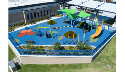 Elevated view of a play space outside a building with swings, climbers, slides, and outdoor musical instruments.